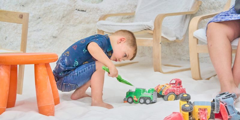 boy-playing-with-toy-trucks-in-a-salt-cave-during