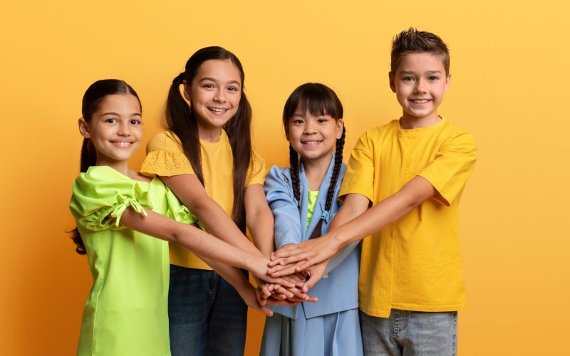 Positive diverse teenagers holding hands on top of each other